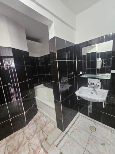 a black and white bathroom with a sink and a tub at Complex GEC-HISTRIA Mamaia in Mamaia