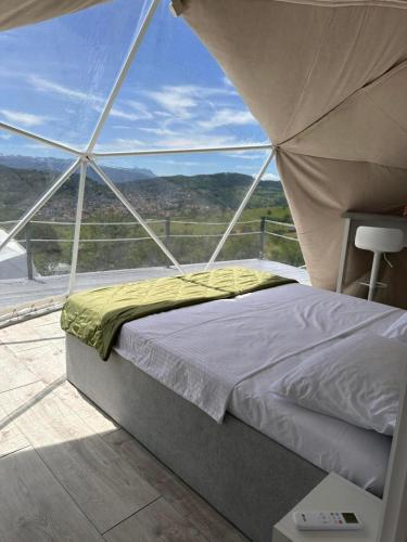 a bed in a room with a large window at Džipsi glamping resort in Sarajevo