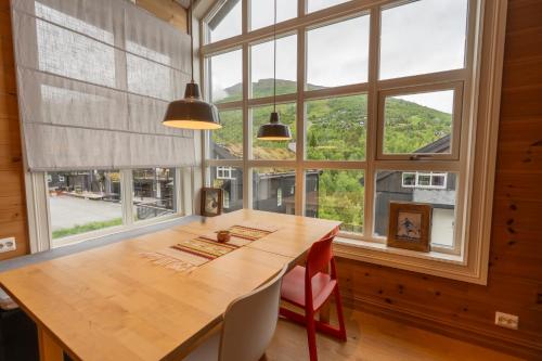 a dining room with a wooden table and large windows at Stranda Fjellgrend 36B in Stranda