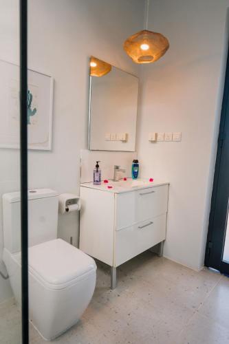 a white bathroom with a toilet and a mirror at Casa Blanca Bweleo in Bweleo