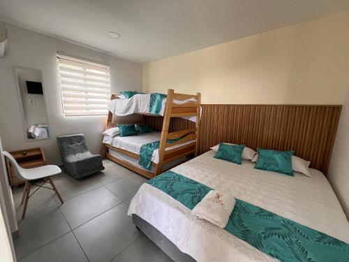 a small bedroom with two beds and a chair at CASA HOTEL SANTA INES in Mompós