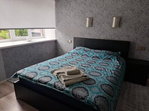 a bedroom with a bed with a blue comforter and two windows at Korter kesklinna piirkonnas in Tartu