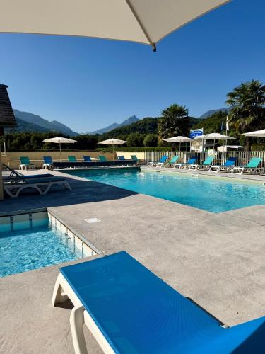 a large swimming pool with chairs and an umbrella at Camping Familial - Parc Aquatique - Grande Aire de Jeux à la Montagne in Agos-Vidalos