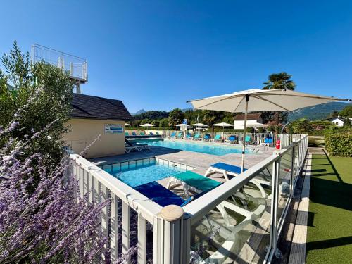 a balcony with a swimming pool with an umbrella at Camping Familial - Parc Aquatique - Grande Aire de Jeux à la Montagne in Agos-Vidalos