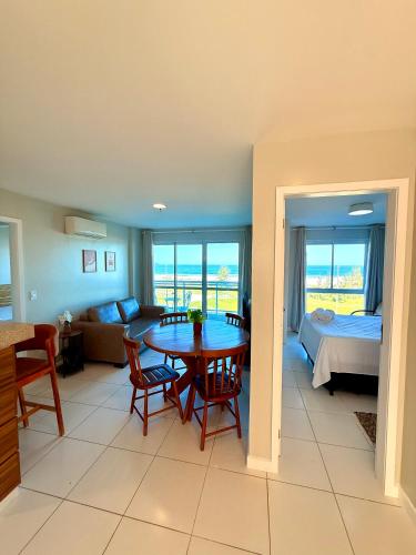 a living room with a table and a bedroom at Mandai Apartamentos in Cabo Frio