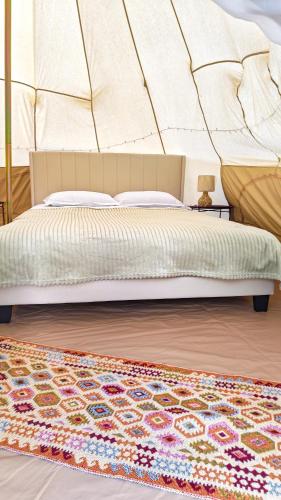 a bedroom with a bed and a rug at Pura Vida Mountain Glamping-tiny houses and tents in Moieciu de Jos