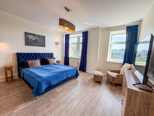a bedroom with a blue bed and a tv in it at Cozy Apartment Kaija in Liepāja