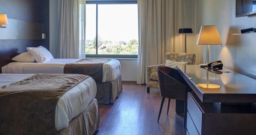 a hotel room with two beds and a desk at Regency Park Hotel in Montevideo
