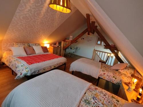 a attic room with two beds and a staircase at Le fenil du Grand Dormeur - Chambres d'hôtes in Bischoffsheim