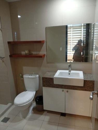 a bathroom with a toilet and a sink and a mirror at Condo in Mactan Newtown in Lapu Lapu City