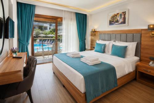 a hotel room with a bed and a desk and a window at Sarum Çeşme in Çeşme