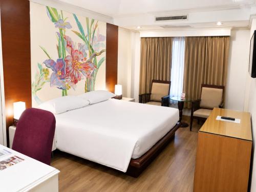 a hotel room with a white bed and a desk at The Palazzo Hotel in Bangkok