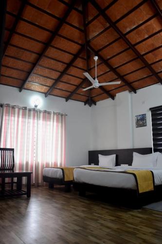 a bedroom with two beds and a ceiling fan at Hotel Gateway Inn in Kushālnagar