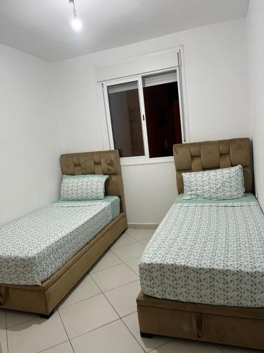 two beds sitting next to each other in a bedroom at Apartamento Familiar con Piscina en Bayt Al Bahr Asilah in Asilah