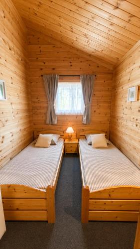 two beds in a log cabin with a window at Chalet le Chal'Heureux in Mauroux