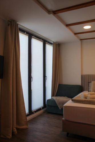 a room with large windows with a bed and a couch at Studio Henigman in Dolenja Vas