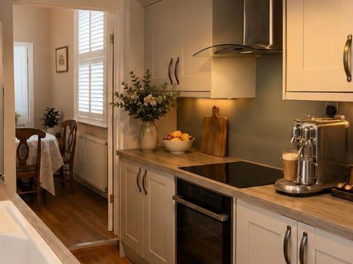 a kitchen with white cabinets and a bowl of fruit on the counter at The Lily Pad - Boutique Townhouse, a short walk to Town Center and Racecourse in Cheltenham