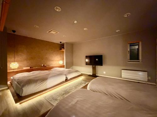 a bedroom with two beds and a flat screen tv at Grand Opening SORA Yunokawa Penthouse in Hakodate