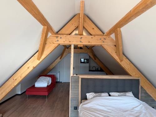 a attic room with a bed and a red chair at Charmant studio climatisé Kintzheim in Kintzheim