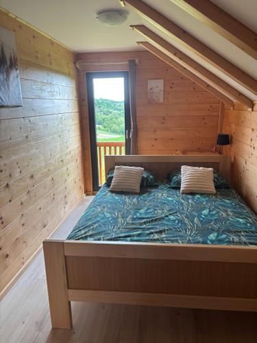 a large bed in a wooden room with a window at Apartman Andrej in Kolarec