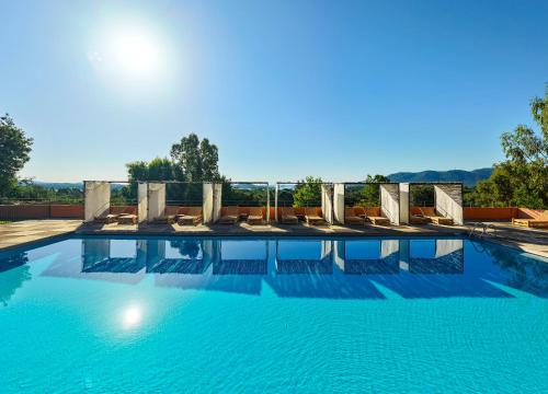 a swimming pool with chairs and blue water at Royal Palm in Porto-Vecchio