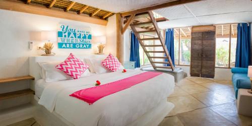a bedroom with a large white bed with pink accents at Sunrise Resort in Gili Islands