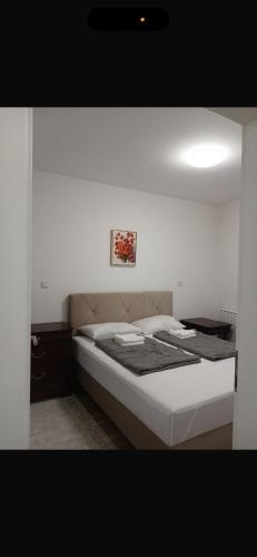 ein Bett in einem Schlafzimmer mit einer weißen Wand in der Unterkunft Central Square in Tuzla