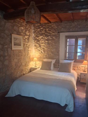 a bedroom with a large bed in a stone wall at Le Vieux Moulin de Jouques in Jouques