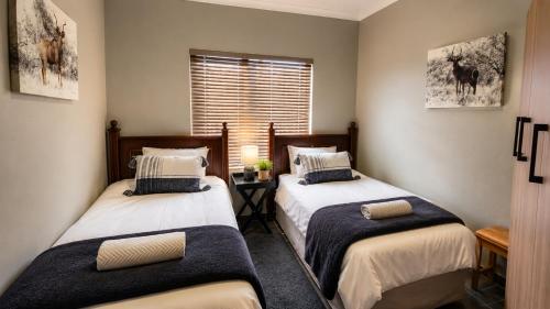 two beds in a room with a window at Lloyds - unit 10 in Ermelo