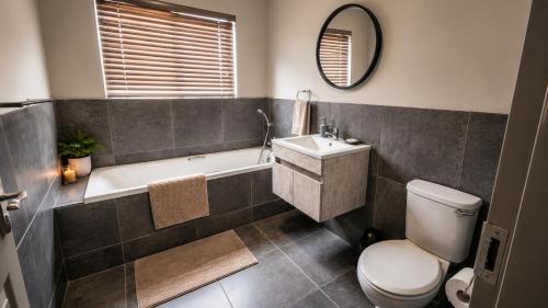 a bathroom with a tub and a toilet and a sink at Lloyds - unit 10 in Ermelo