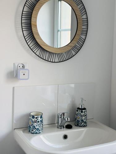 a bathroom sink with a round mirror above it at Pokoje gościnne Agroturystyka in Gierałtów