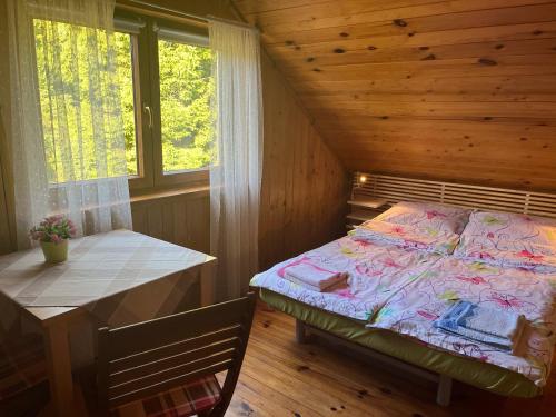 a bedroom with a bed and a table and a window at Dom Gaja in Ińsko