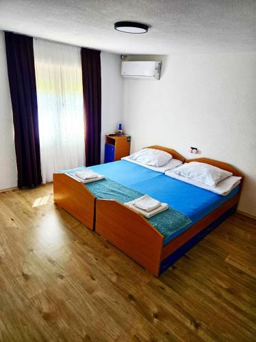 a bedroom with a large wooden bed with blue sheets at Villa Sara - Apartments & Garden, Kratovo in Kratovo