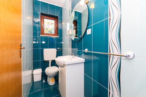 a blue tiled bathroom with a toilet and a sink at Vikendica Donji Humac in Donji Humac