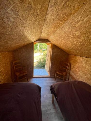 a room with two beds and two chairs and a window at Camping de la Pelouse in Jaulny