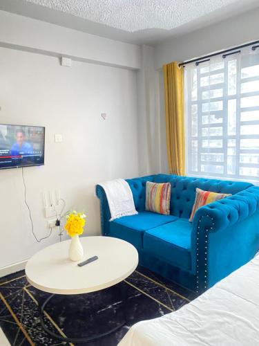 a living room with a blue couch and a table at Lucky House Studio in Nanyuki