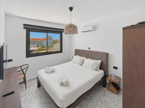 a bedroom with a bed with white sheets and a window at The Retro Suite Kato Paphos 2 min to the beach in Paphos