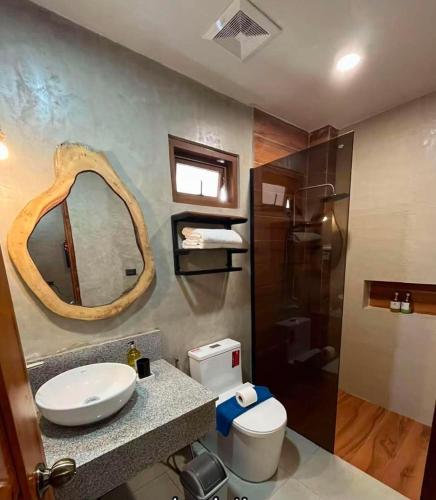 ein Badezimmer mit Waschbecken, Toilette und Spiegel in der Unterkunft Balay Isabel in San Juan
