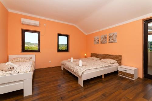two beds in a room with orange walls and wooden floors at Vikendica Donji Humac in Donji Humac