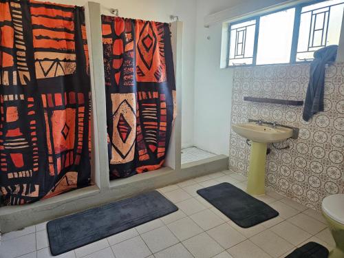 a bathroom with a shower curtain and a sink at Tambuki Backpackers & Self-catering - Dinokeng in Hammanskraal