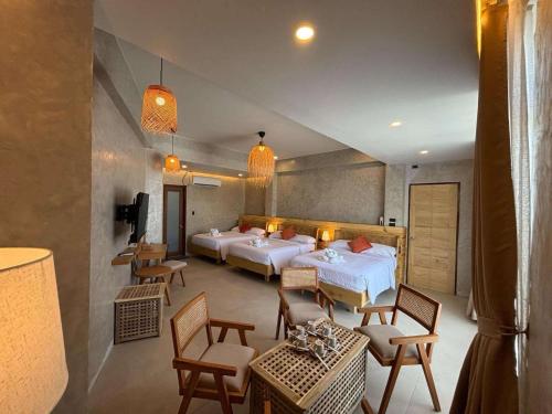 ein Hotelzimmer mit zwei Betten, Tischen und Stühlen in der Unterkunft Balay Isabel in San Juan