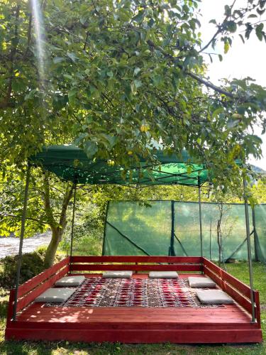 a red bed with a canopy under a tree at Apartman Elma in Jajce