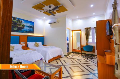 a hotel room with two beds and a tv at Mount Zion Holidays in Kuttālam
