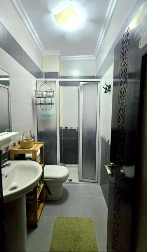 a bathroom with a shower and a toilet and a sink at Olas Appartement Escapade Méditerranéenne à Martil Confort & Proximité Plage in Martil