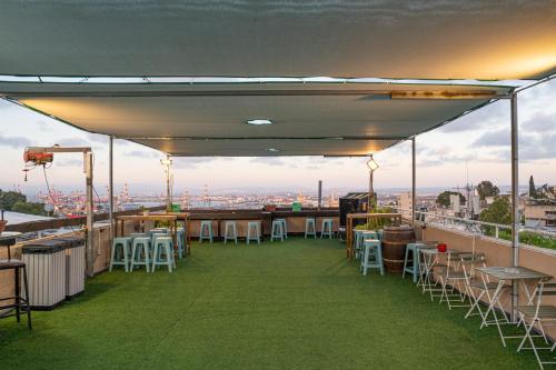 eine Terrasse mit Tischen und Stühlen auf einem Dach in der Unterkunft Hotel Loui Talpiot in Haifa