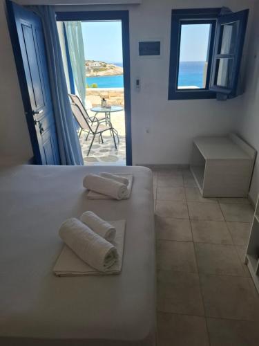 a bedroom with two towels on a bed with a view of the beach at Vrahos Rooms - Studios in Alopronia