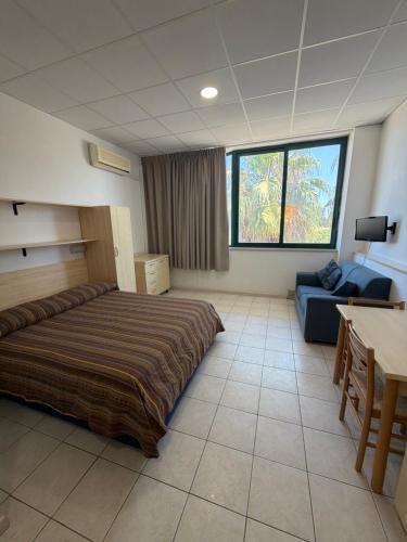 a bedroom with a bed and a table and a couch at Polena Residence Hotel in Marina di Montenero