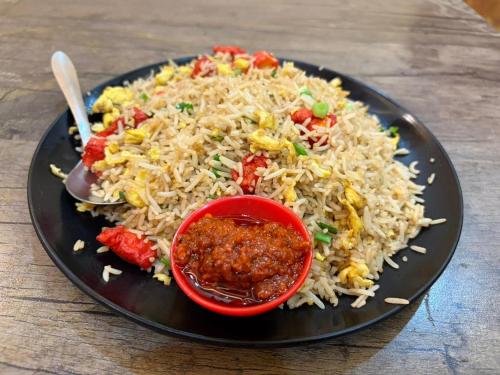 a plate of rice with a red bowl of sauce at SH Guest House Malvan in Malvan