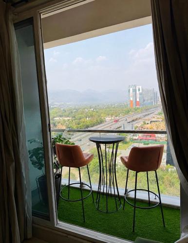 a balcony with two chairs and a table and a window at Designer One Bedroom Apartment With Balcony & Mountain Views Opposite Centaurus Mall ISB in Islamabad