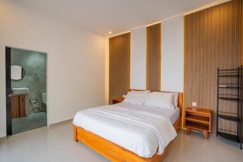 a bedroom with a large bed and a bathroom at Villa Dake Tanah Lot in Tanah Lot